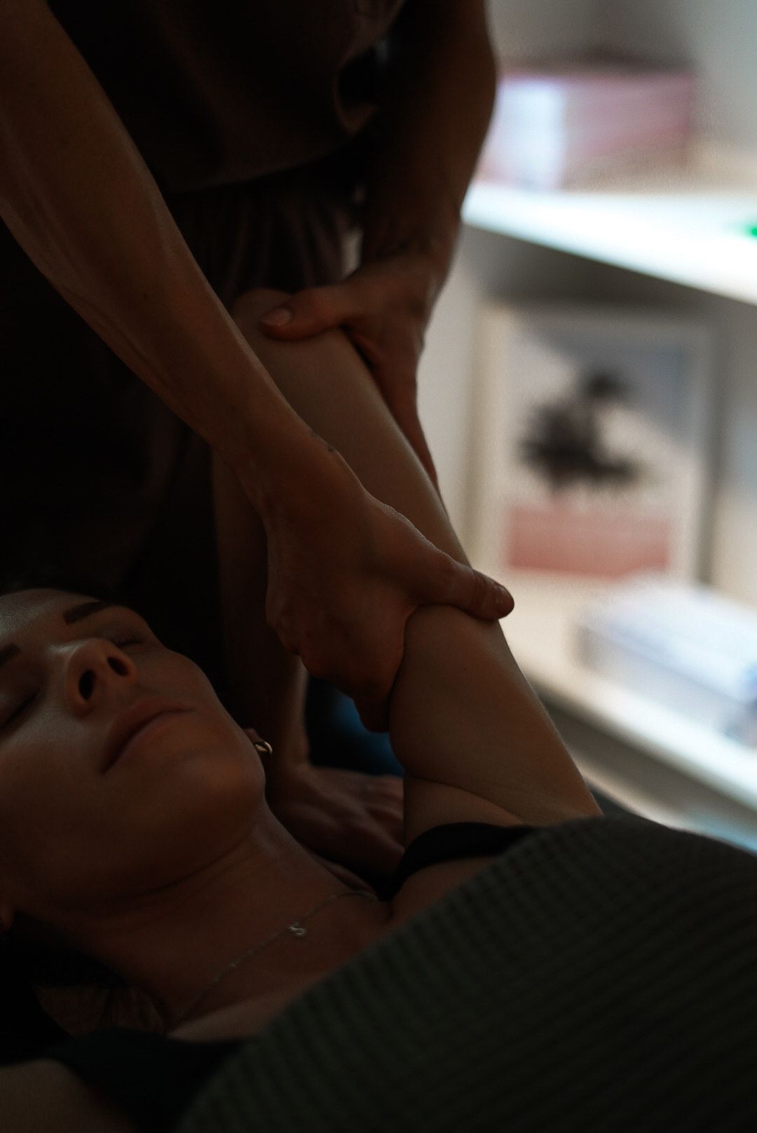 Woman receiving arm massage in a well-lit room. Practitioner's hands on her arm.