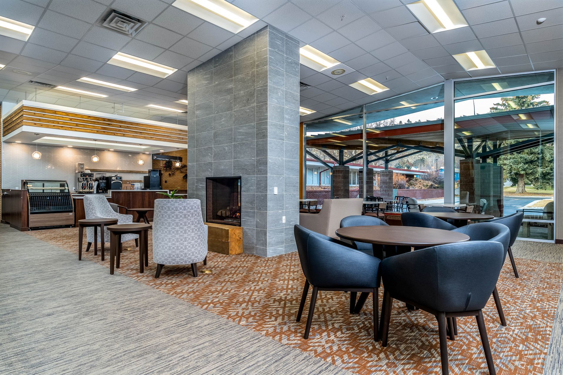 A large room with tables and chairs and a fireplace.