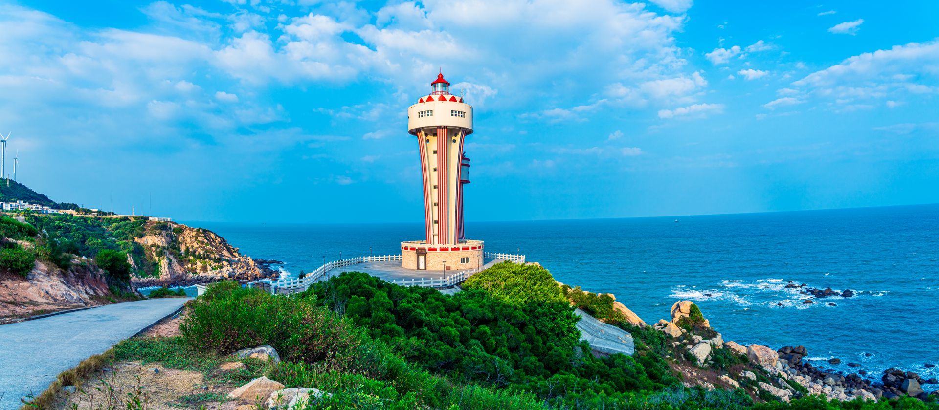 A lighthouse is sitting on top of a cliff overlooking the ocean.