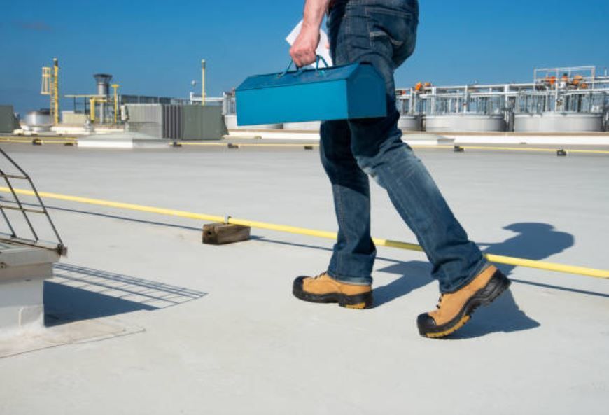 Worker carrying tool box on large commercial rooftop