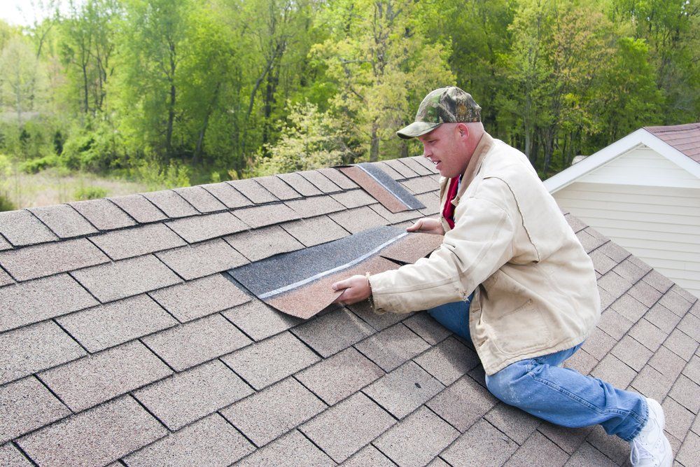 Man repairing shingles on rooftop