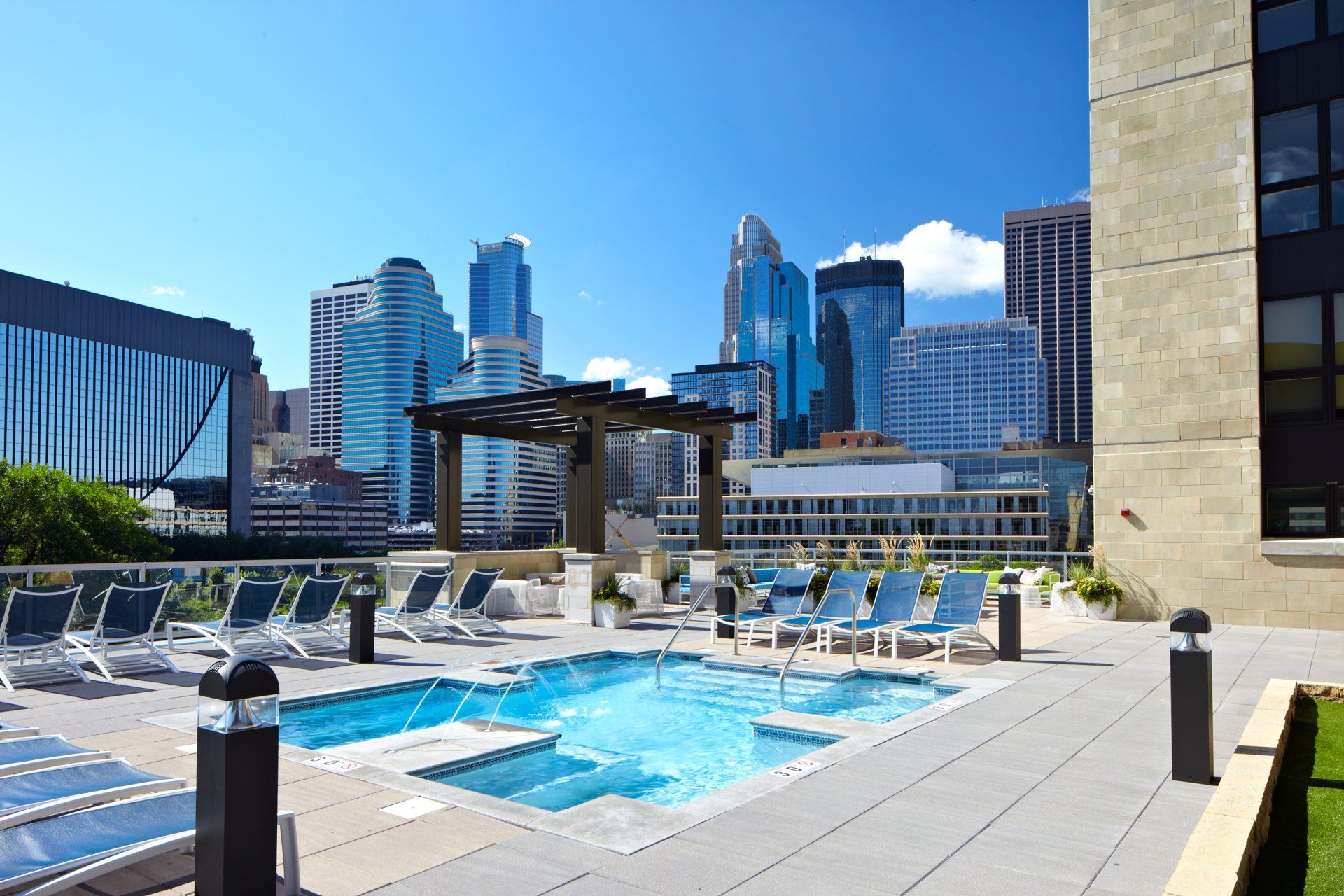 A large swimming pool with a city skyline in the background at 222 Hennepin Apartments.