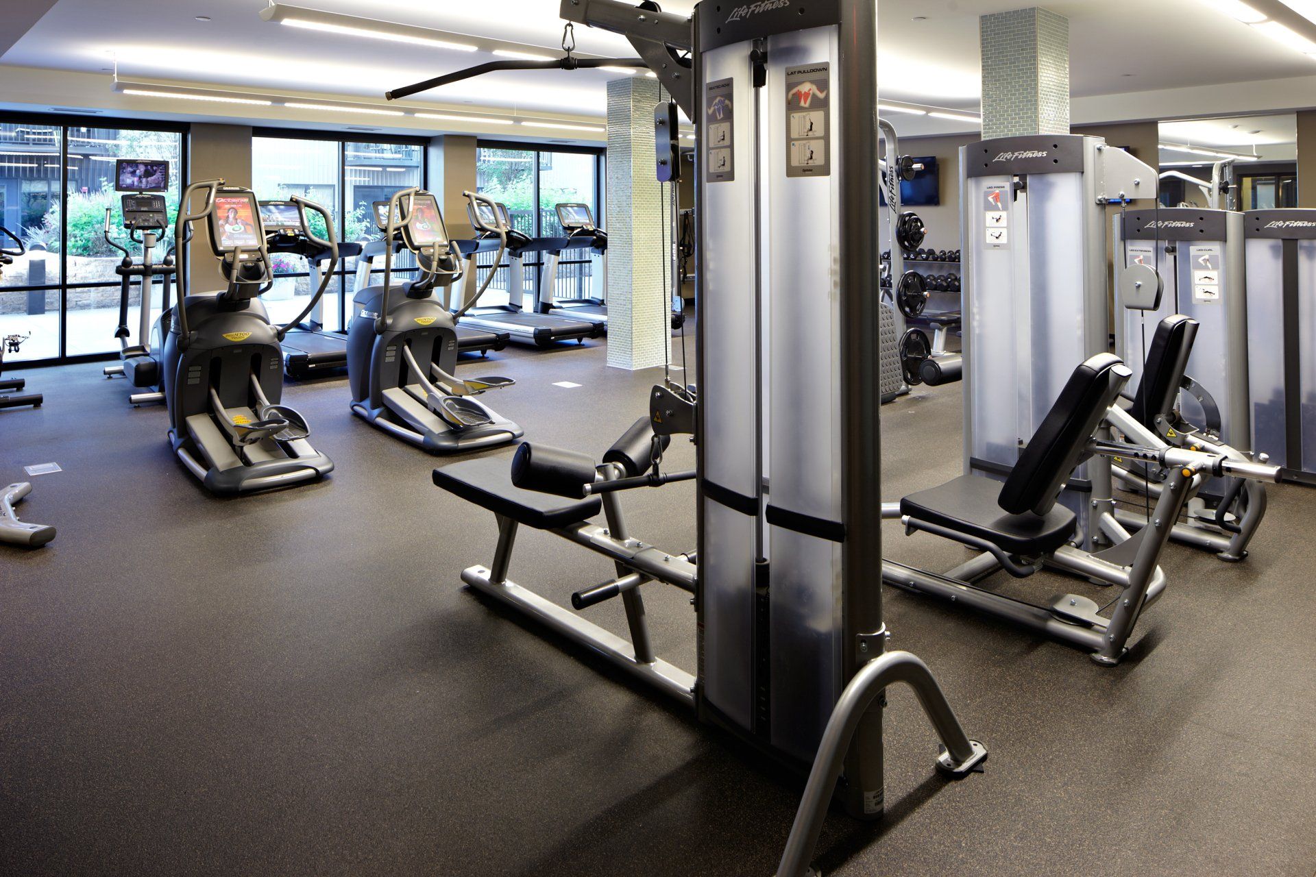 A gym with a row of treadmills and a bench at 222 Hennepin Apartments.