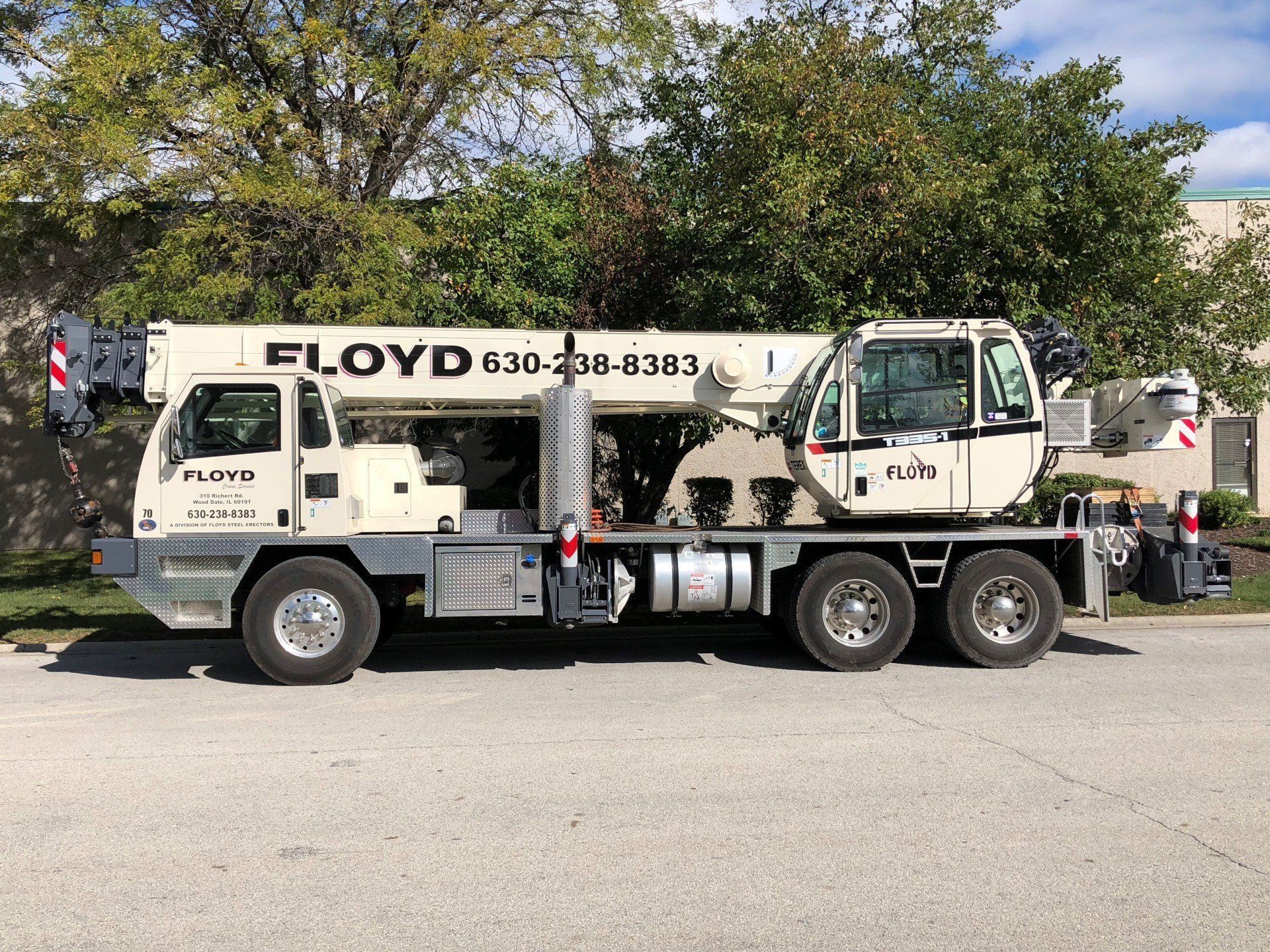 Tow truck with “FLOYD” logo parked on a street beside trees and a cloudy sky Tow truck with “FLOYD” logo parked on a street beside trees and a cloudy sky