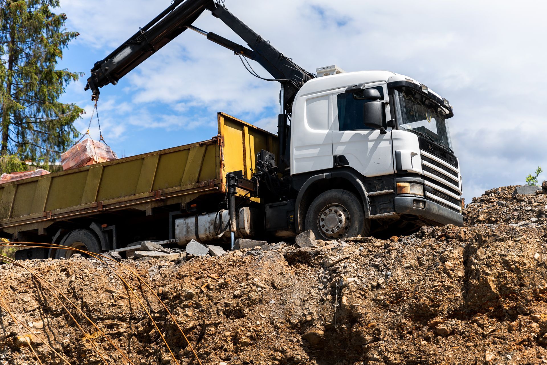Truck unloading dirt at a construction site under a blue sky