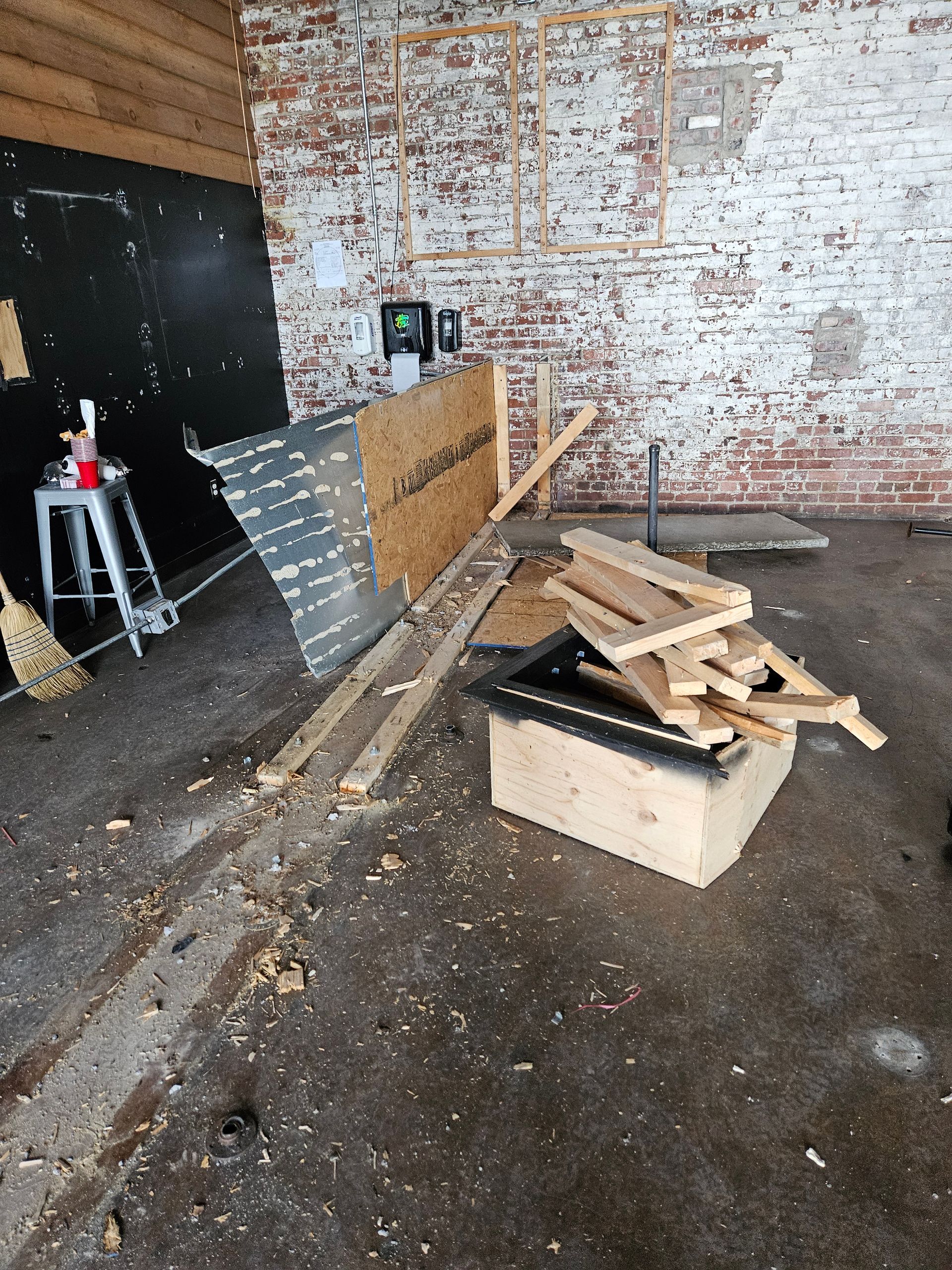 A pile of wood in a room with a brick wall