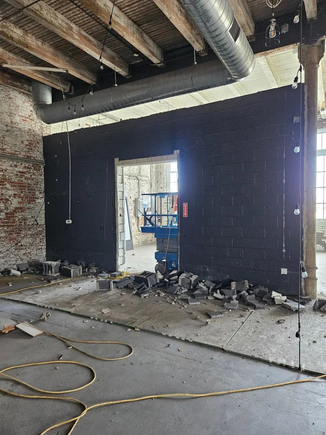 A large brick wall is being demolished in a building under construction.