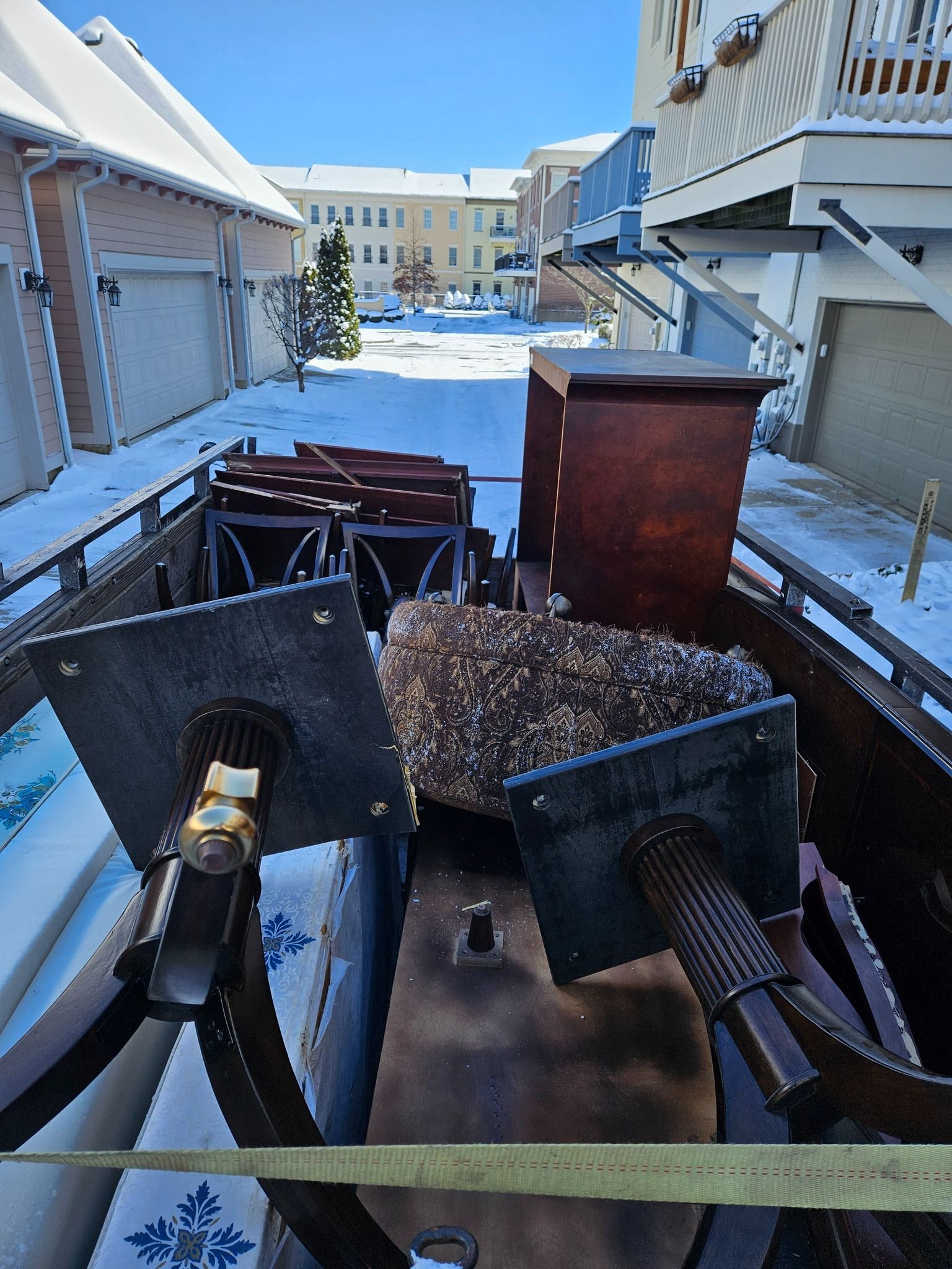 A pile of furniture is sitting on the sidewalk next to a fence.