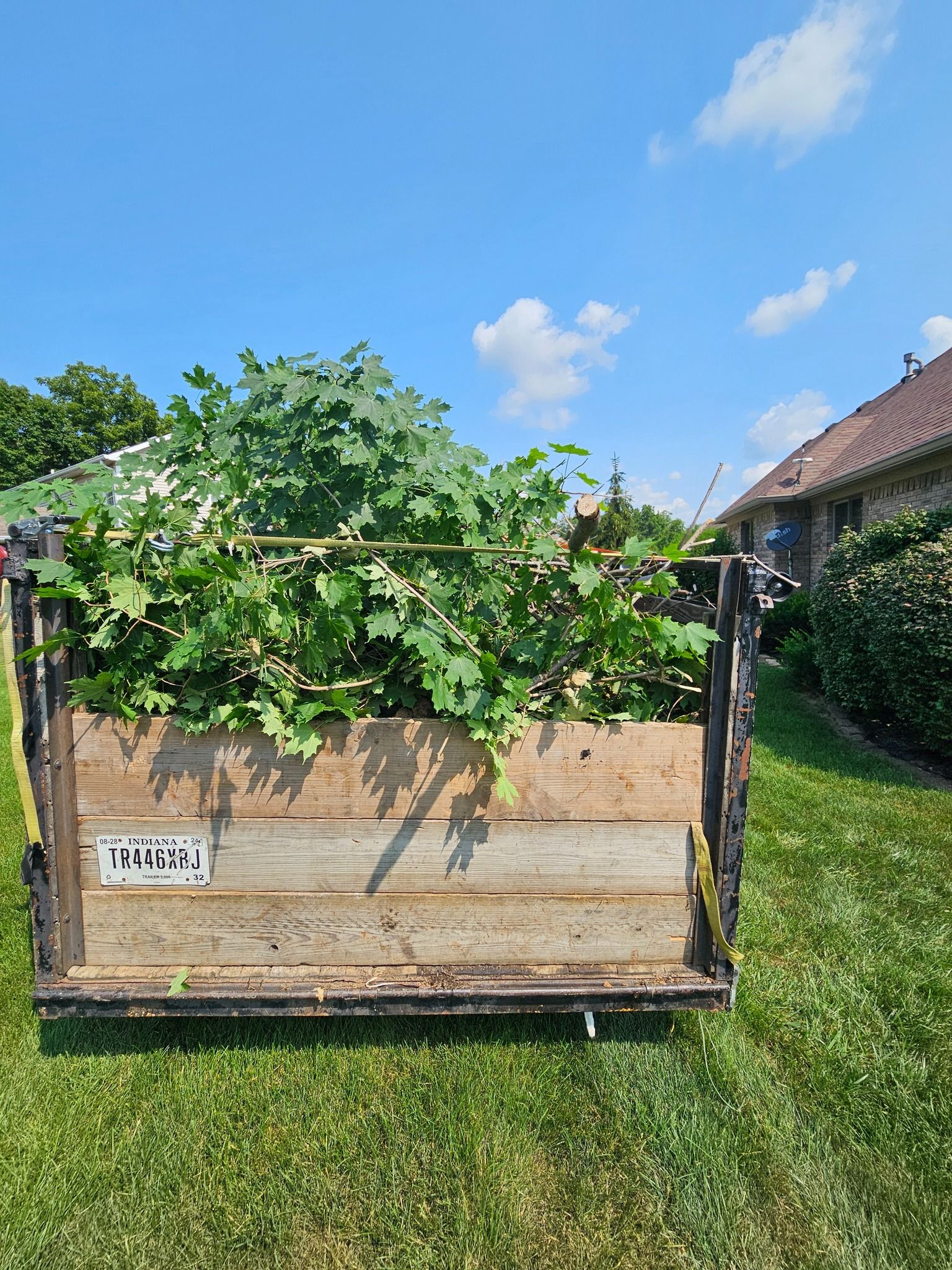 A blue shed is sitting in the grass in front of a white house.