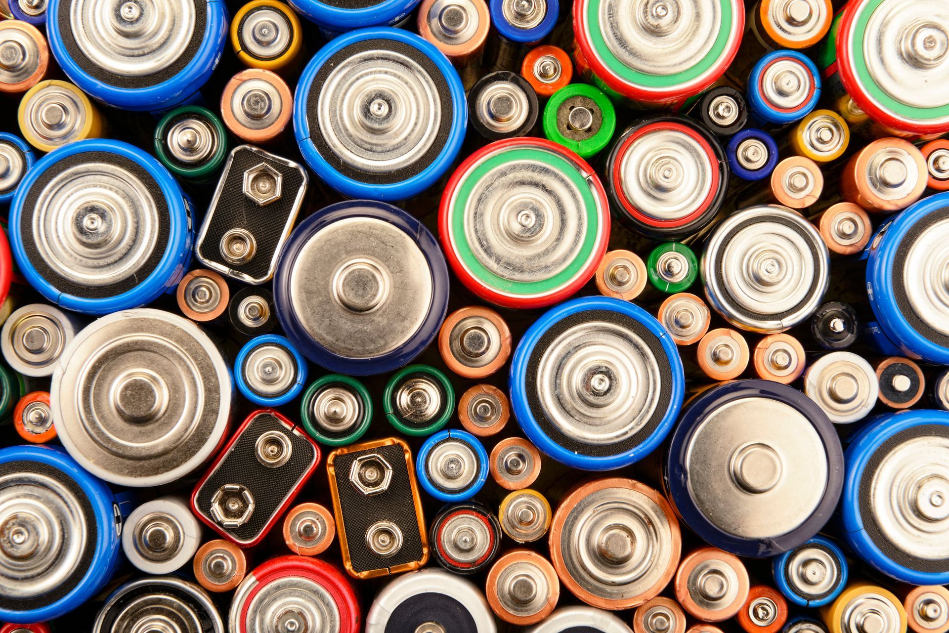 A bunch of different types of batteries are stacked on top of each other.