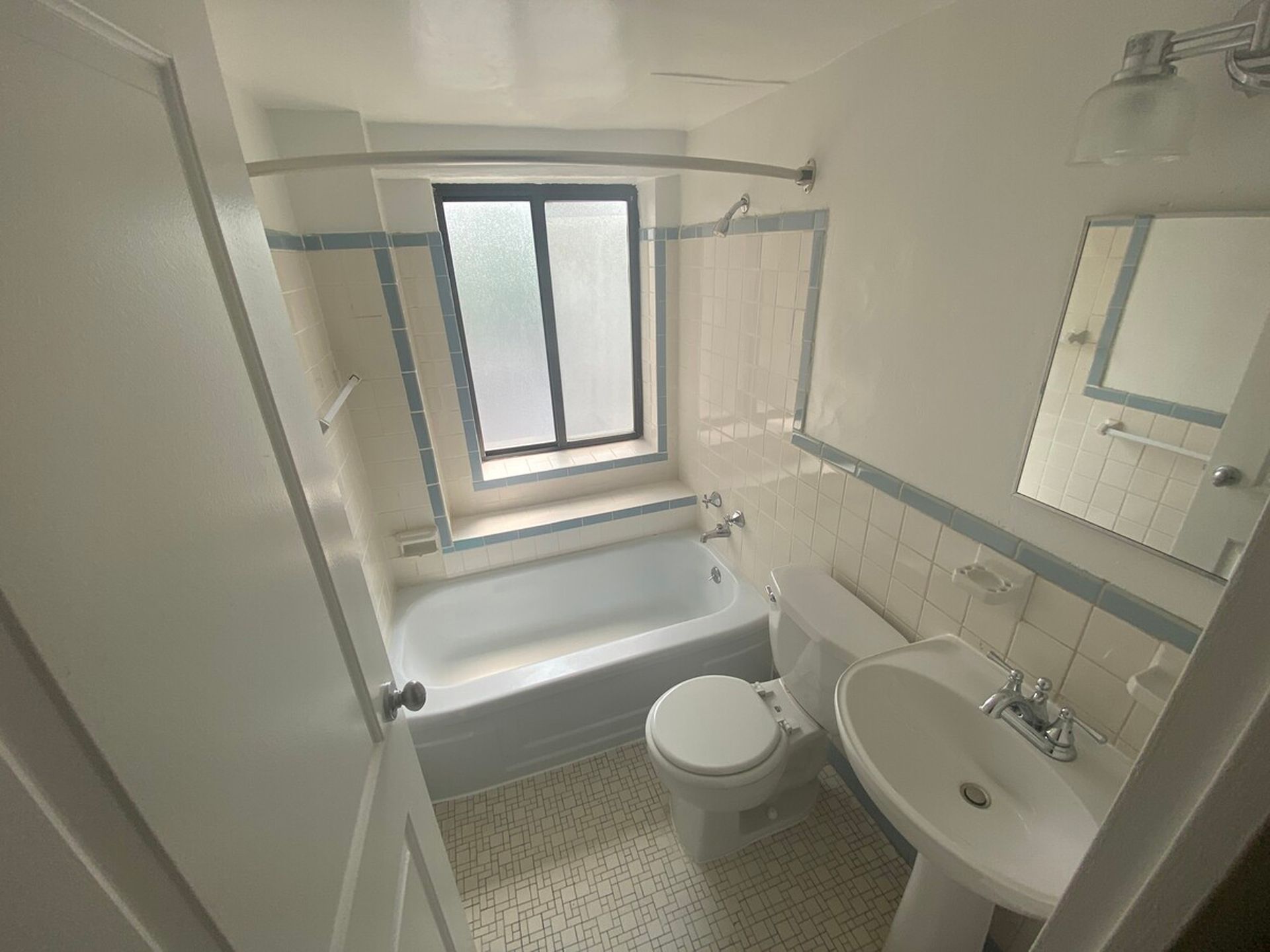 A bathroom with a sink , toilet , tub and window.