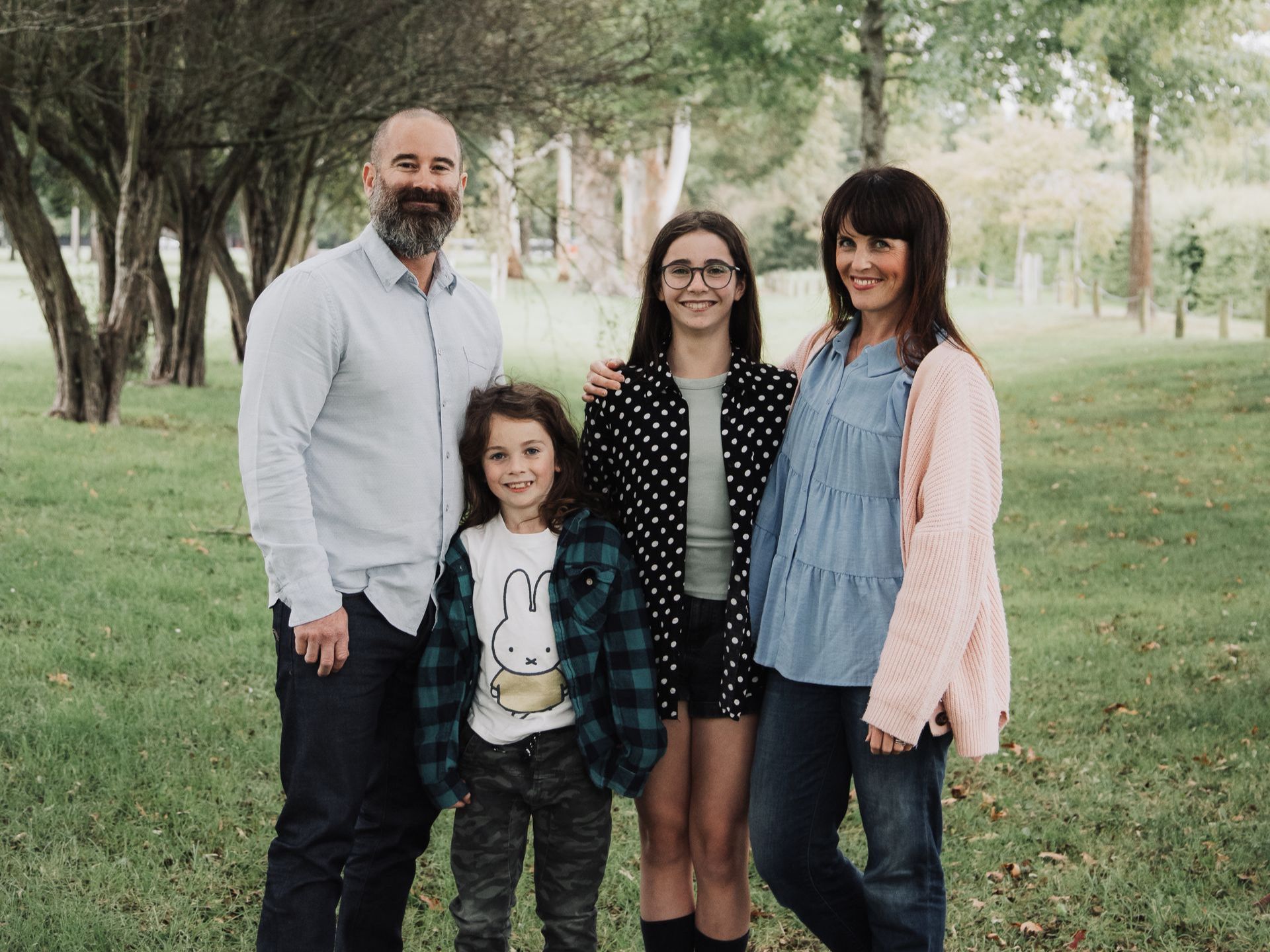 A family is posing for a picture in a park.