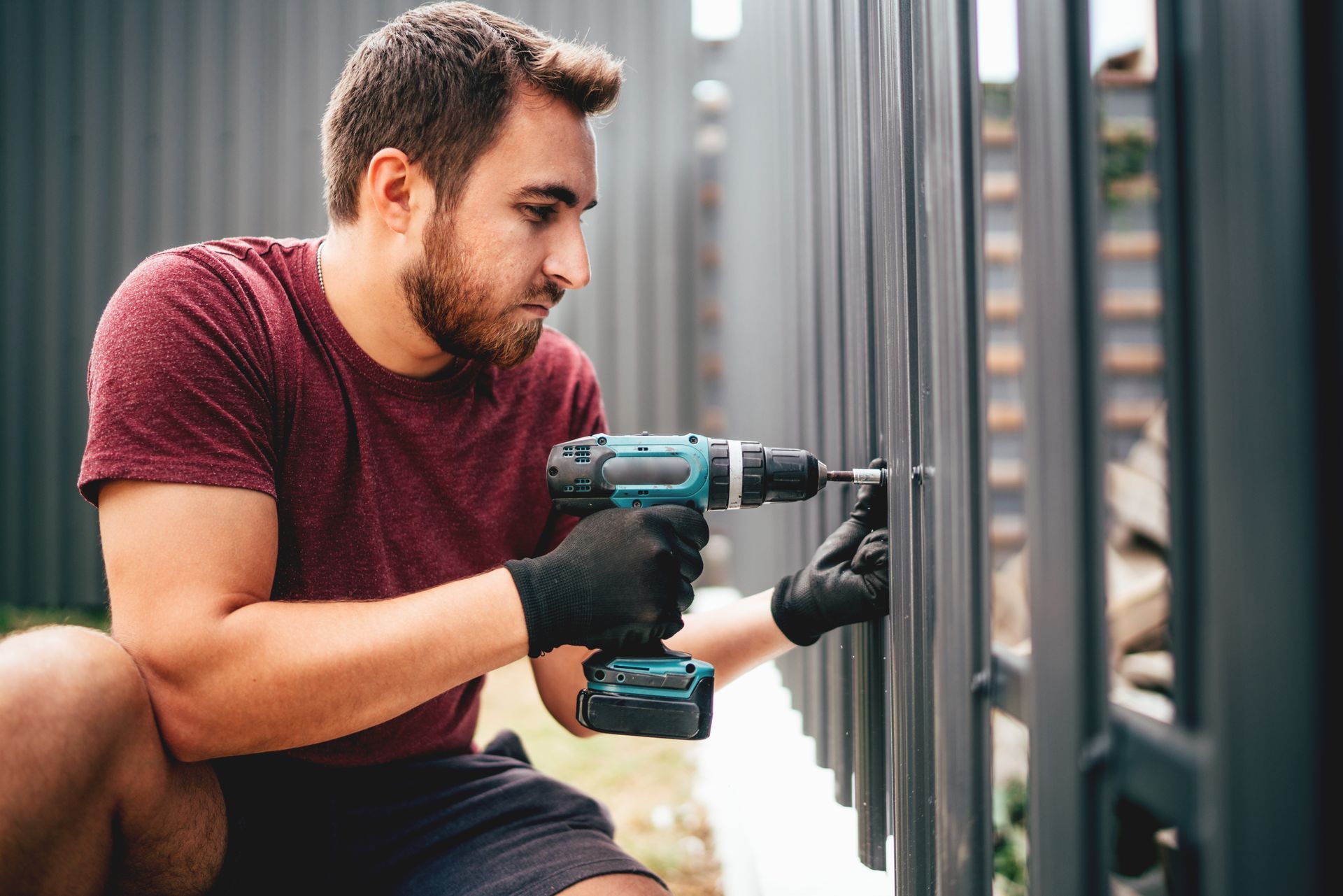 Construction man working with cordless electrical screwdriver on metal fence. Construction man working with cordless electrical screwdriver on metal fence.