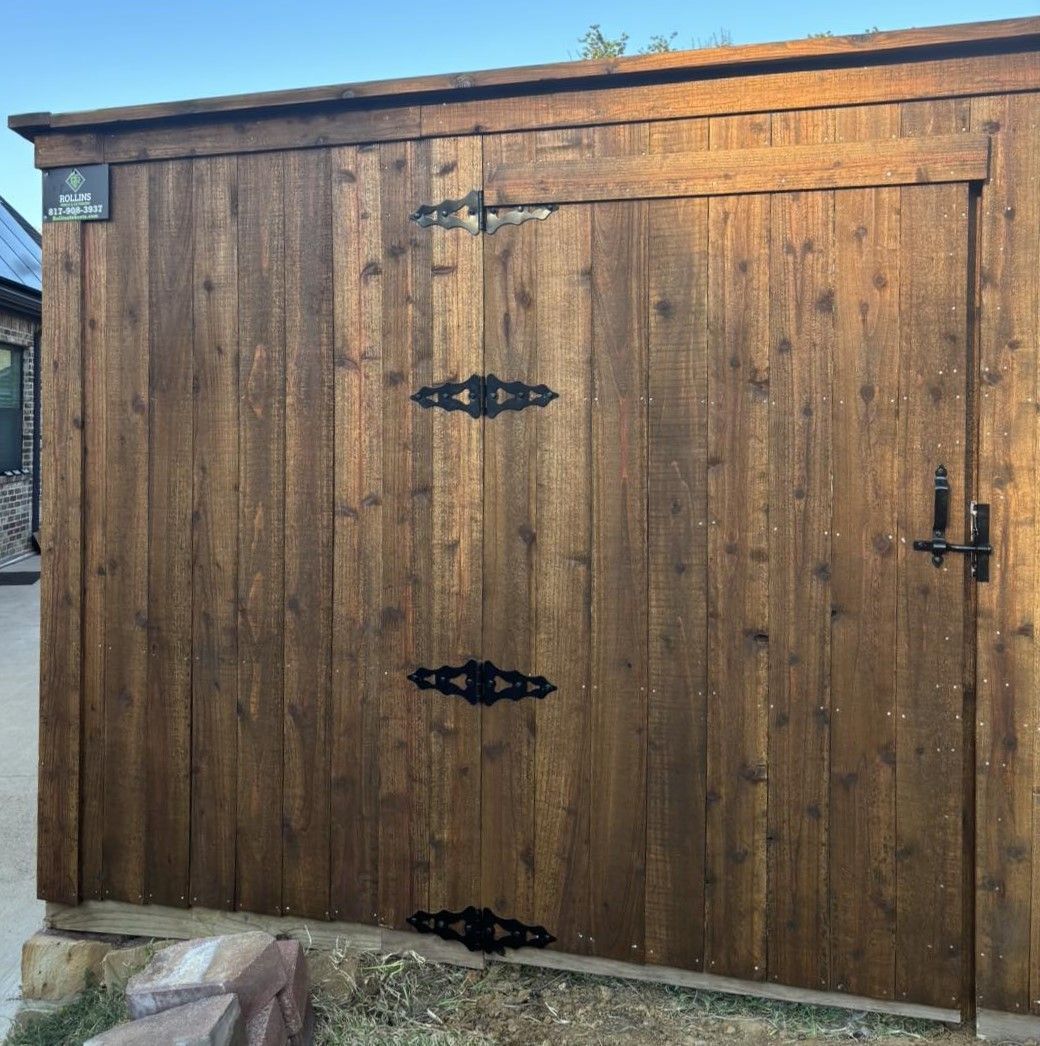 Wooden gate with decorative black hinges and latch. Brown wood, outdoor setting.
