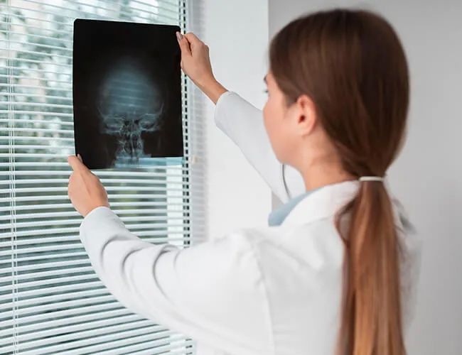 a female doctor is looking at an x-ray of a skull .