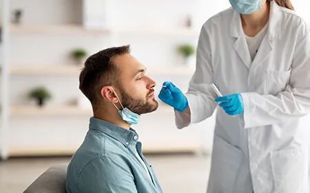 a man is getting a nasal swab from a doctor .