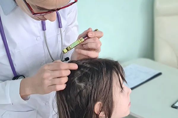 a doctor is examining a little girl 's hair with a stethoscope .