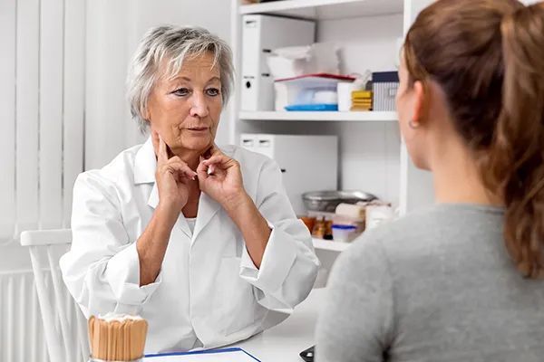 an older woman is talking to a younger woman in a doctor 's office .