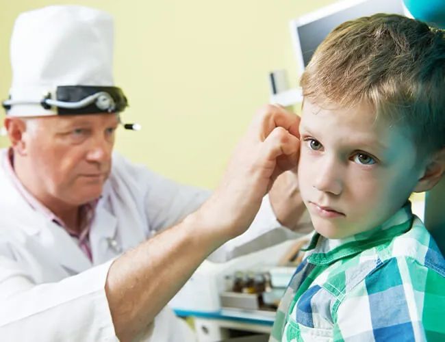 a young boy is getting his ears examined by a doctor .