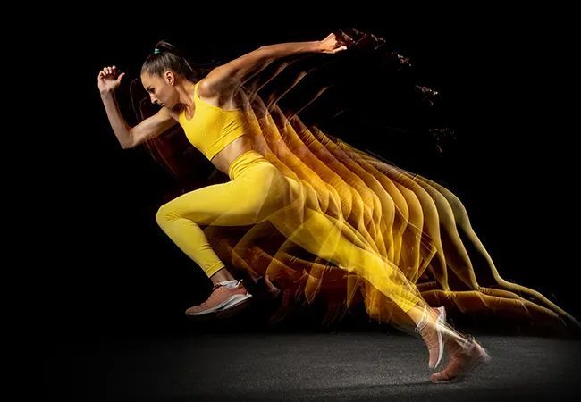 a woman in a yellow outfit is running on a black background .