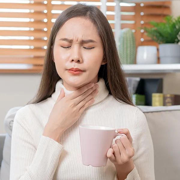 a woman is holding her ear in pain while sitting on a couch .