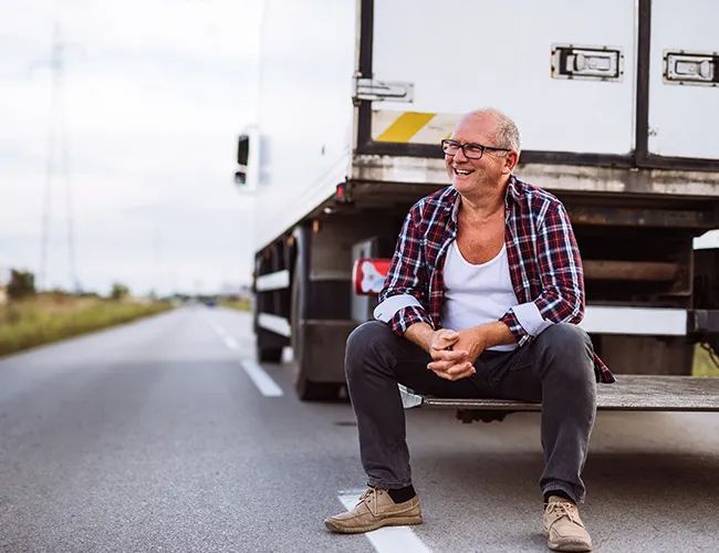 a man is sitting on the back of a truck on the side of the road .