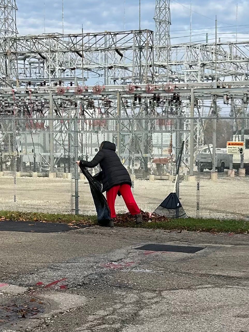 a man in red pants is sweeping the ground in front of a power plant .