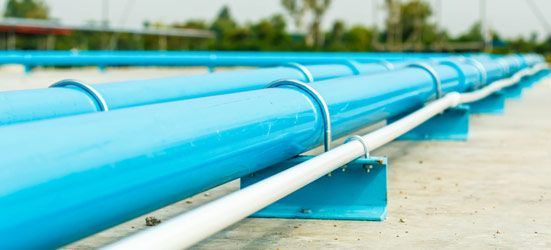 A Row of Blue Pipes Sitting on Top of a Concrete Surface — Elite Wastewater Solutions in Bowral, NSW