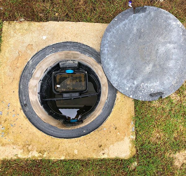 A Manhole Cover With the Lid Open and a Meter Inside of It — Elite Wastewater Solutions in Goulburn, NSW