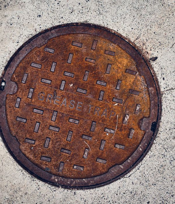 A Rusty Manhole Cover With the Words Grease Trap Written on It — Elite Wastewater Solutions in Fitzroy Falls, NSW