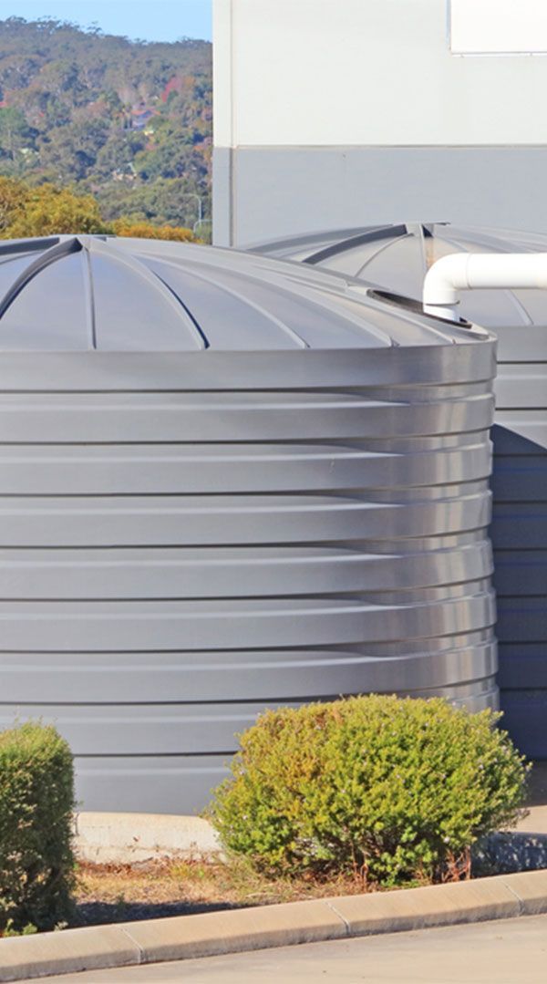 A Large Black Water Tank is Sitting in Front of a Building — Elite Wastewater Solutions in Fitzroy Falls, NSW