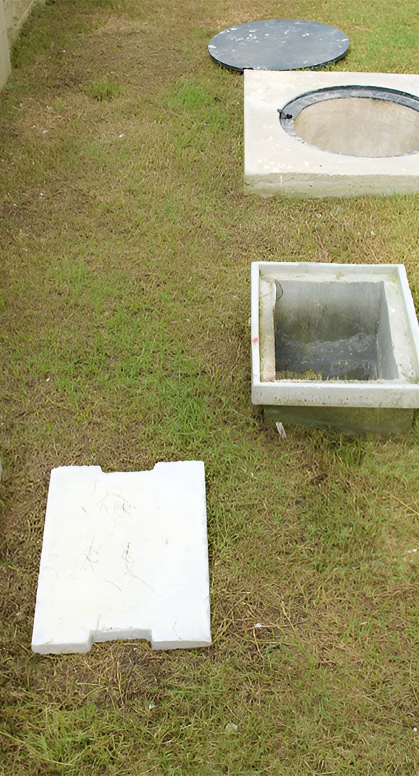A Manhole Cover is Sitting on Top of a Lush Green Field — Elite Wastewater Solutions in Goulburn, NSW