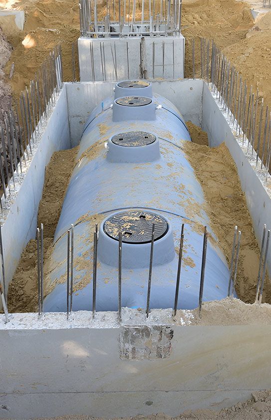 A Large Blue Tank is Sitting in a Hole in the Ground — Elite Wastewater Solutions in Bowral, NSW