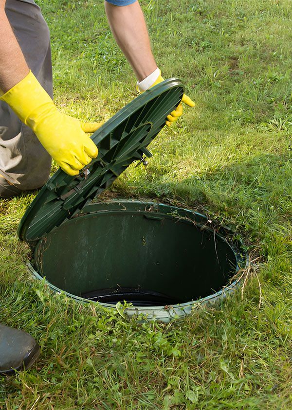 A Man Wearing Yellow Gloves is Opening the Lid of a Septic Tank — Elite Wastewater Solutions in Robertson, NSW
