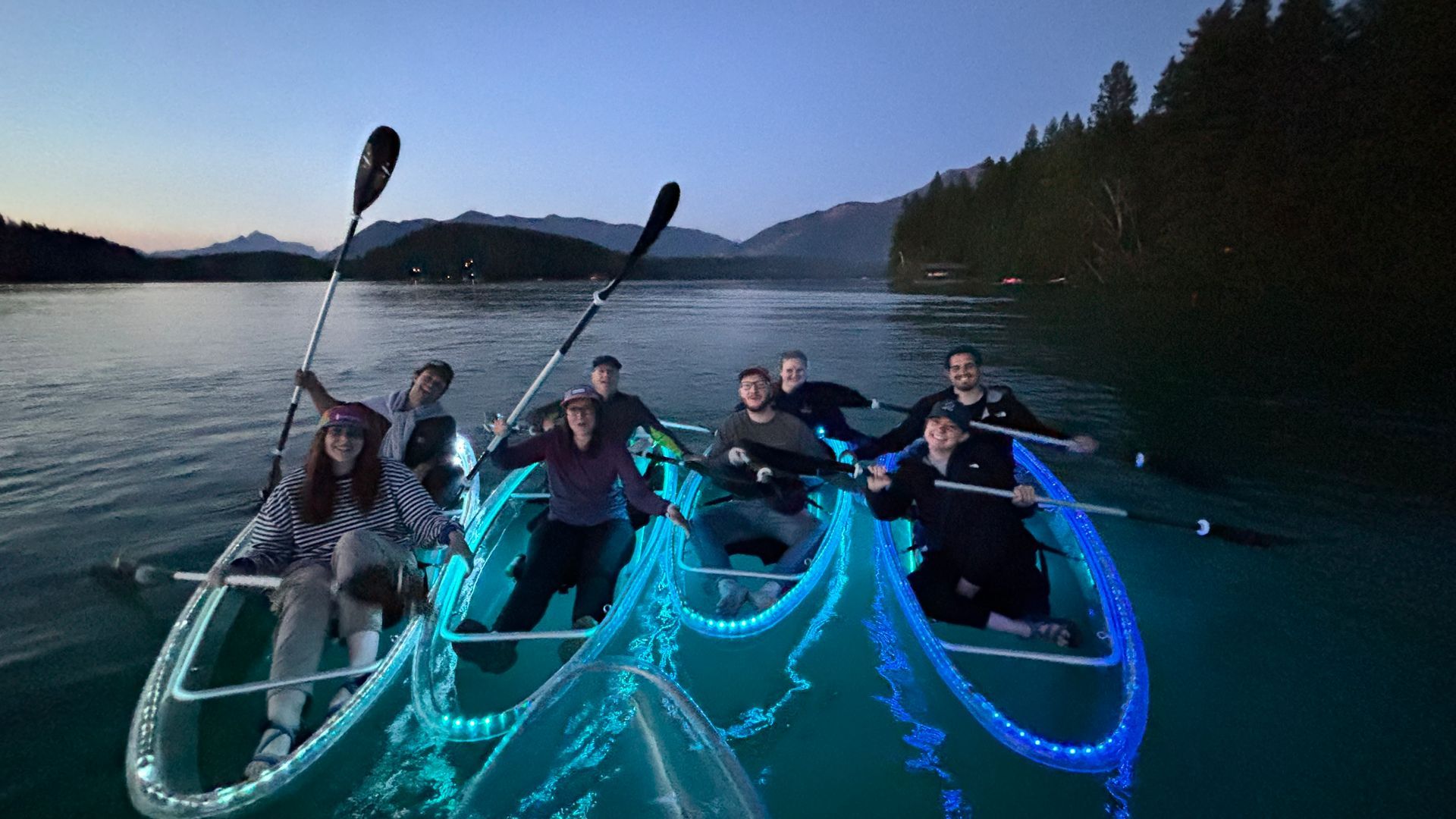 A group of friends on a guided kayaking tour in clear kayaks near glacier park