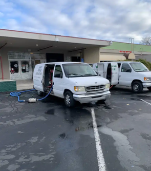 Two white vans are parked in front of a building
