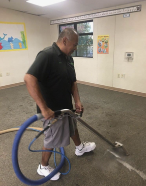A man is cleaning a carpet with a vacuum cleaner