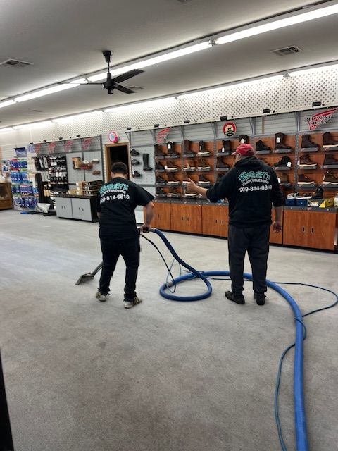 Two men are cleaning the floor of a shoe store