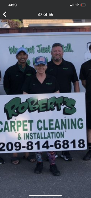 A group of people holding a sign for robert 's carpet cleaning