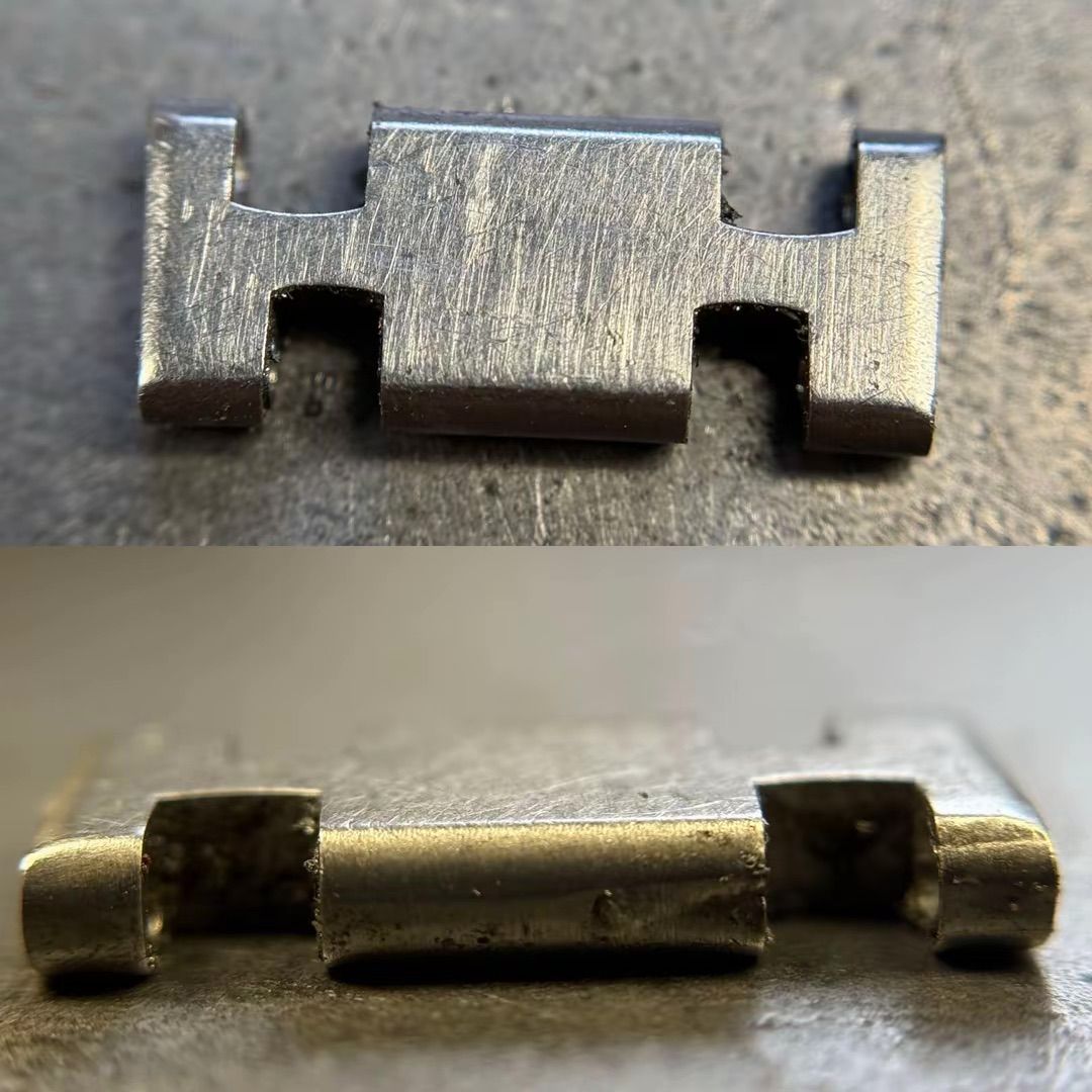 Due viste di una piccola maglia rettangolare in metallo color argento per bracciale di orologio, caratterizzata da tacche ad incastro.