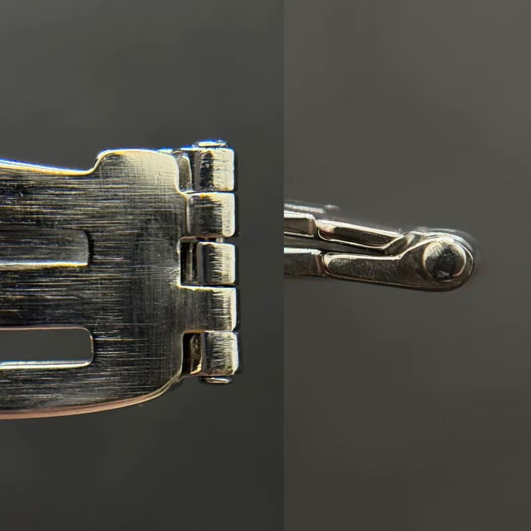 Vista ravvicinata di una chiusura metallica per orologio, che mostra il meccanismo a cerniera e un perno color oro sul lato.