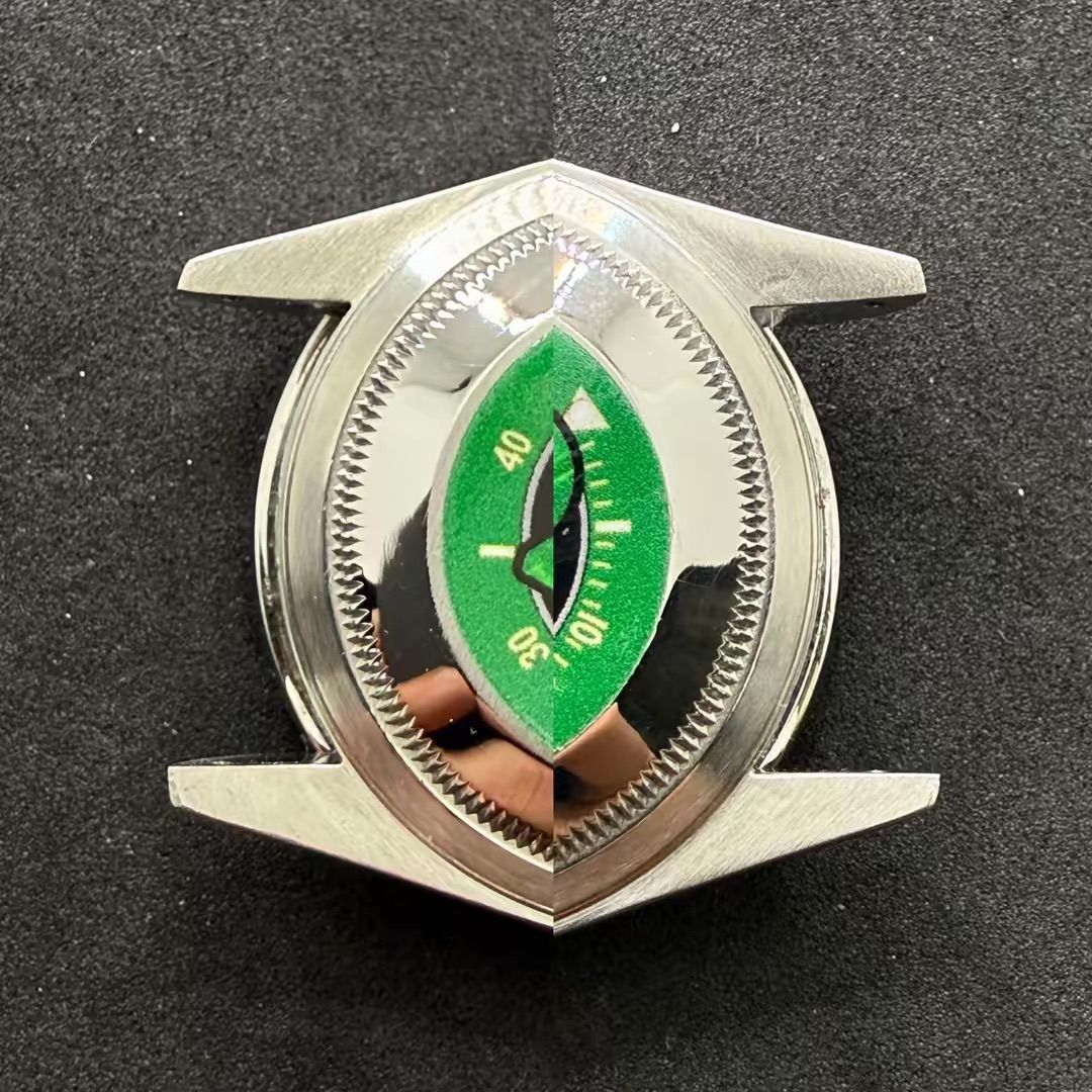 Un quadrante di orologio verde con una scala da 10 a 40 all'interno di una cassa metallica, riflesso in una composizione sdoppiata a specchio.