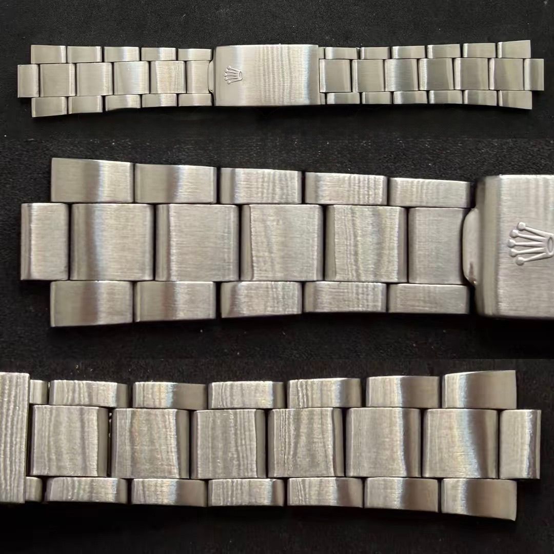 Tre bracciali per orologi in metallo color argento, tra cui uno con il logo della corona Rolex sulla chiusura, disposti su una superficie scura.