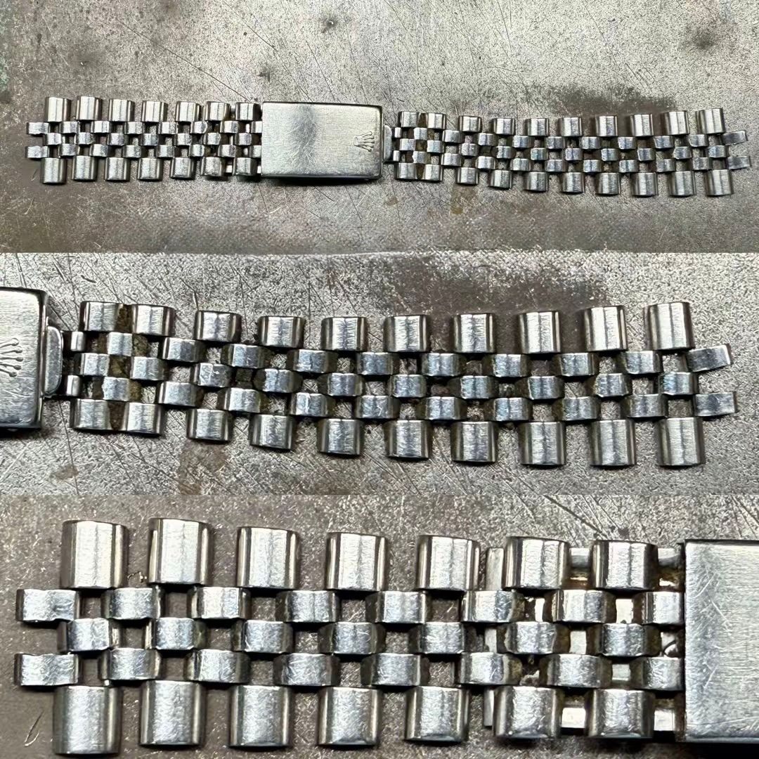 Tre bracciali per orologi in metallo color argento, di larghezza e design delle maglie differenti, sono disposti orizzontalmente su una superficie ruvida.