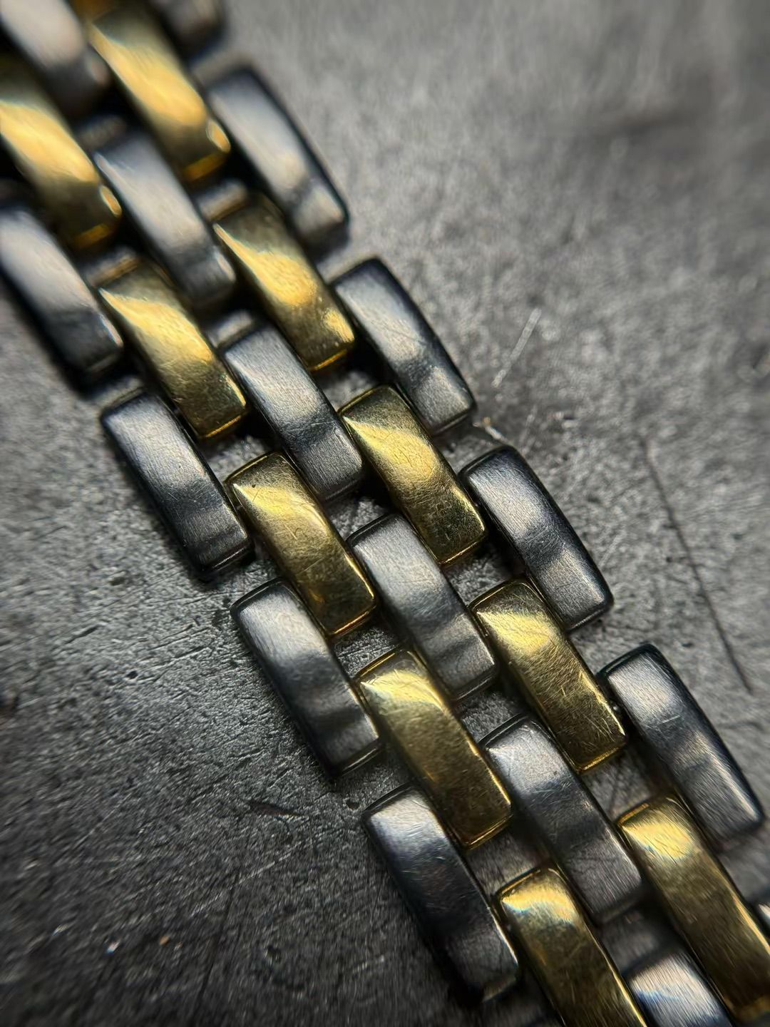 Una vista ravvicinata e angolata di un bracciale per orologio bicolore con maglie alternate color oro e argento spazzolato.