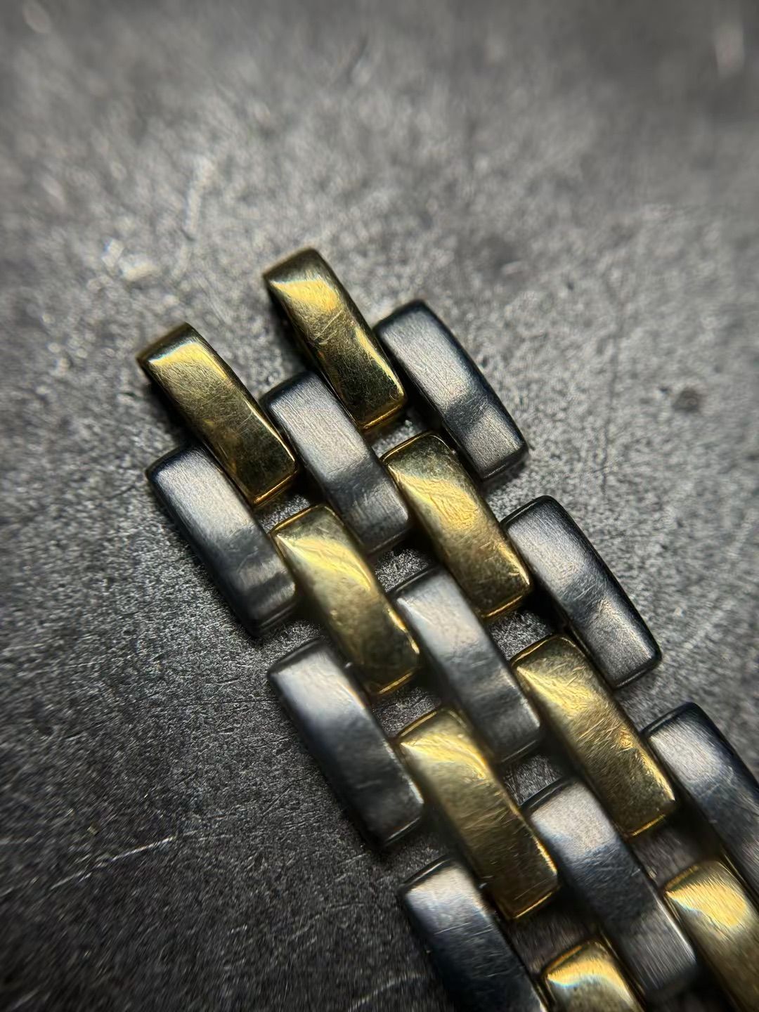 Primo piano di un bracciale per orologio in metallo bicolore argento e oro che mostra le maglie intrecciate.