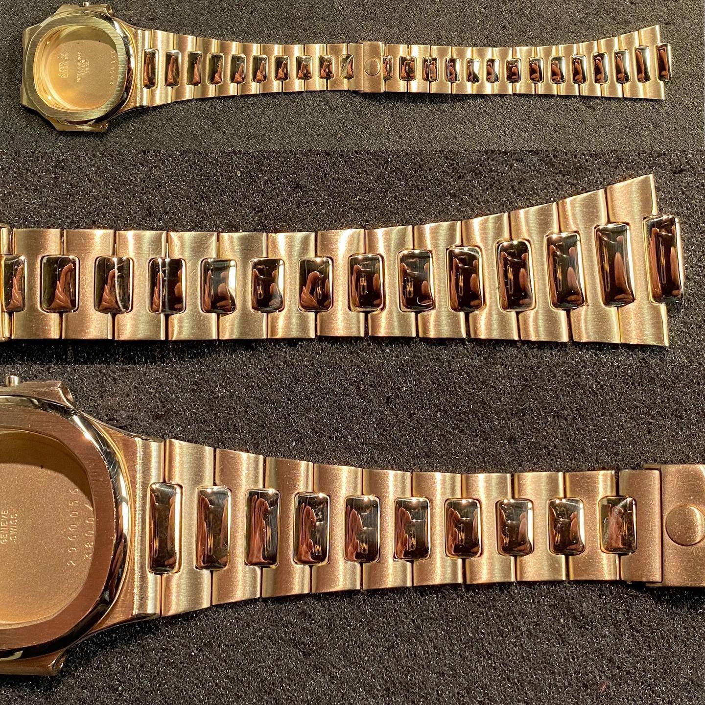 Tre bracciali per orologi color oro rosa e una cassa per orologio disposti orizzontalmente su una superficie grigio scuro testurizzata.