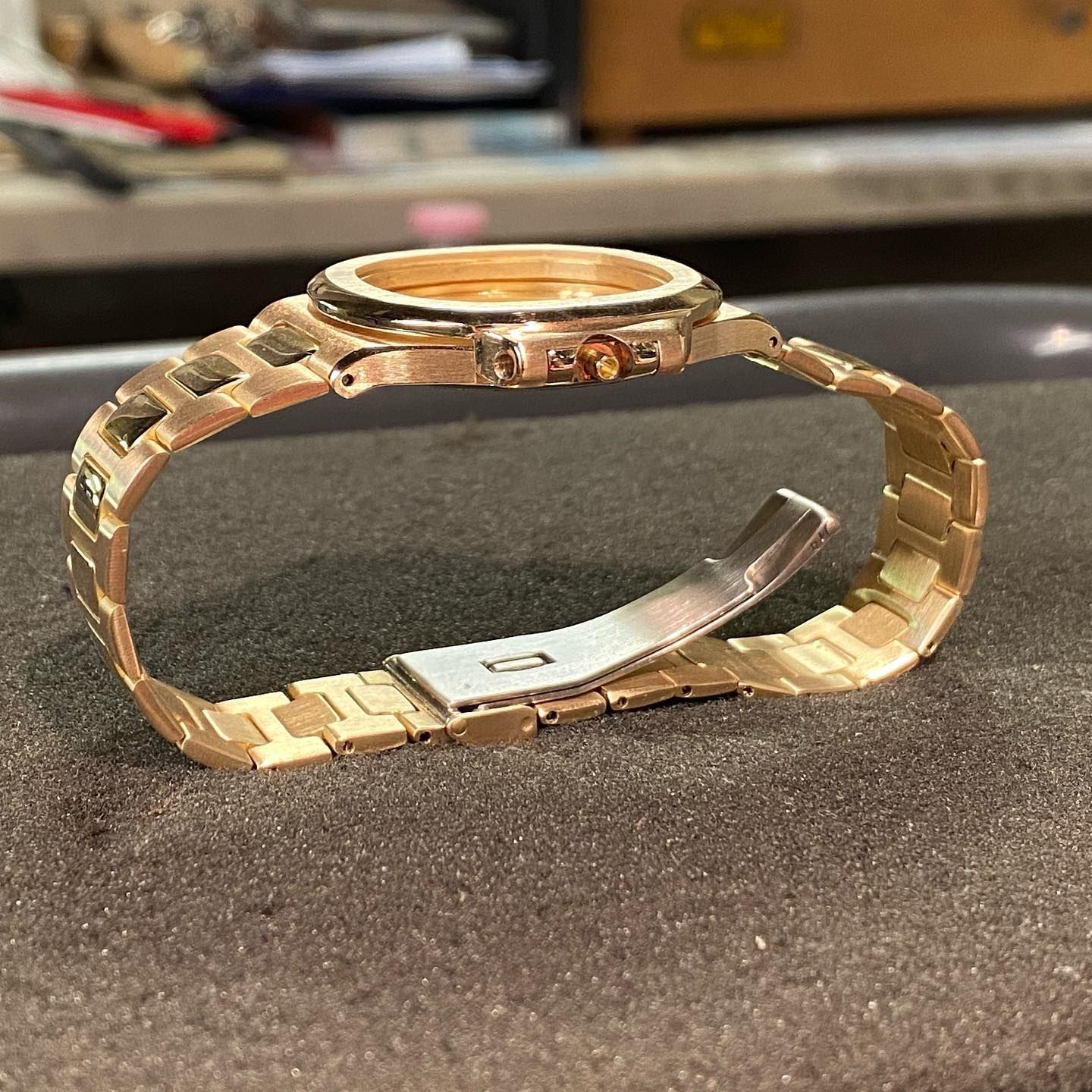 Un orologio in metallo color oro rosa con bracciale a maglie, poggiato su una superficie di schiuma scura.