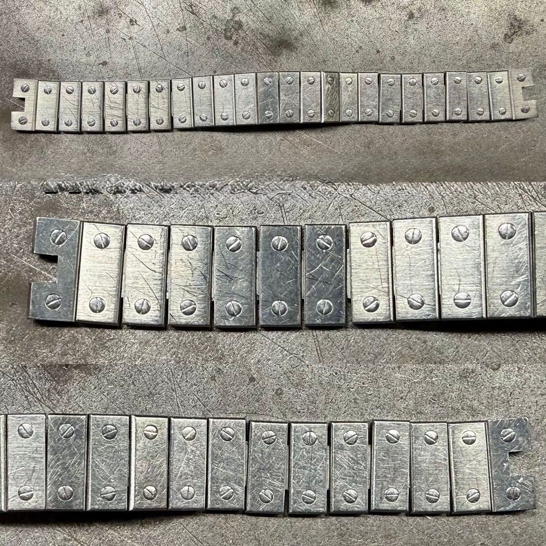 Tre file di contrappesi metallici per ruote, disposte su una superficie grigia ruvida.