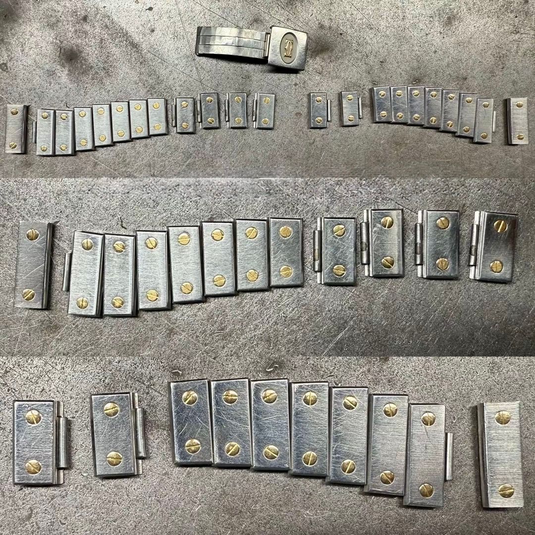 Una serie di cerniere metalliche con perni color ottone, disposte in file su una superficie grigia e ruvida.